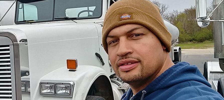 Andrae posing for a selfie in front of his white semi-truck