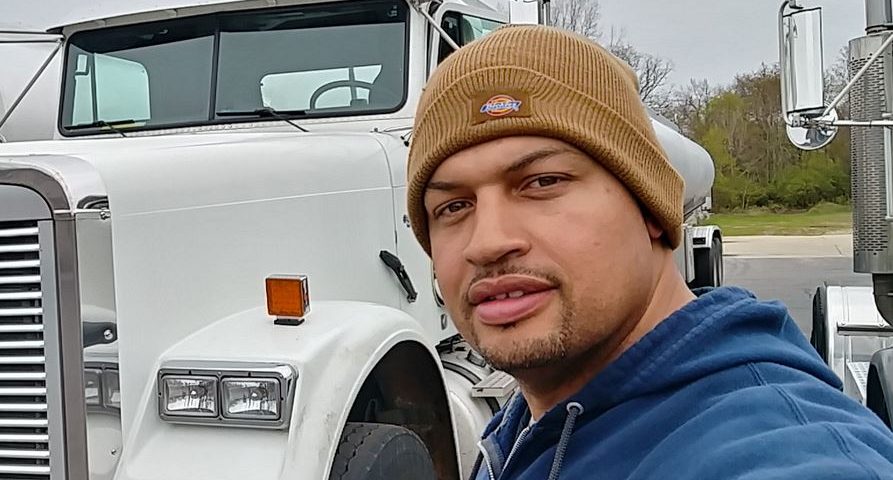 Andrae posing for a selfie in front of his white semi-truck